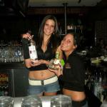 Here we have KATIE posing with AMANDA, and a couple of bottles of their trade. Notice that Katie has the TALL bottle, and Amanda has the SHORT one