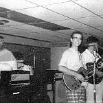 This is an unusual photo. There I (Buzz) am at the organ, and Ronnie is on the drums. I see three guitars in the front line, but No Sax. Where is Rodney?
Who is playing the third guitar? 